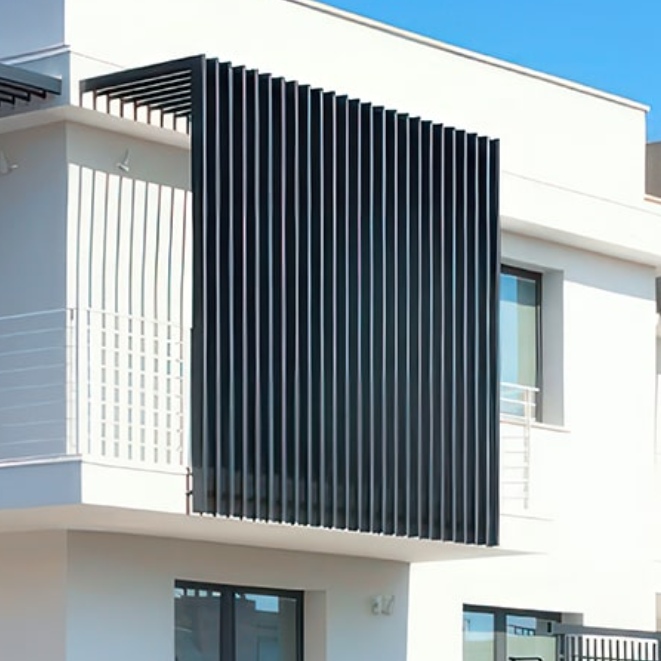 Un moderno edificio bianco con balcone presenta frangisole a listelli in alluminio sulla facciata. Queste stecche verticali proiettano ombre intricate sul muro, completate da grandi finestre che rivelano un cielo azzurro limpido sullo sfondo.